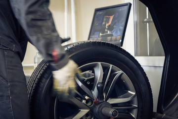 Mechanic worker makes computer wheel balancing on special equipment machine tool