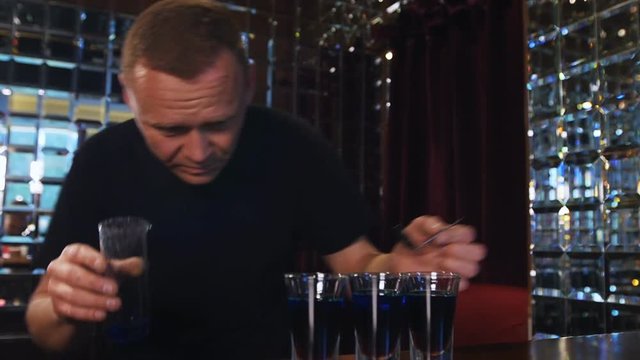 bartender preparing and lining shot glasses for alcoholic drinks on bar