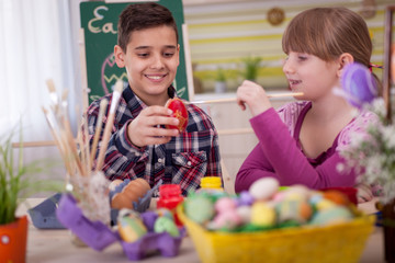 Obraz premium Two smiling kids paint easter eggs