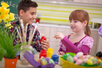 Obraz na płótnie Canvas Two smiling kids paint easter eggs