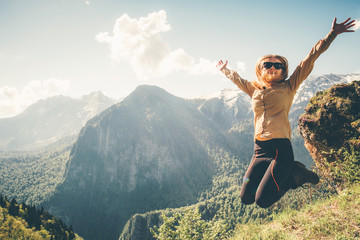 Happy Woman jumping up raised hands mountains on background Lifestyle Travel emotional success...
