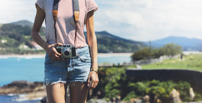 Tourist traveler photographer making pictures sea scape on vintage photo camera on background ocean, hipster girl enjoying peak mountain and nature holiday, mock up ocean waves view, blurred backdrop