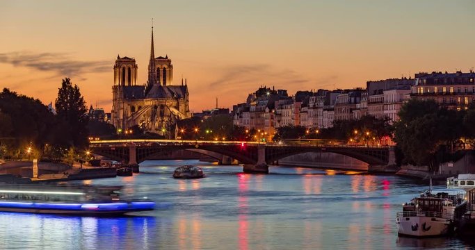 Notre Dame de Paris Cathedral, Ile Saint Louis and the Seine River at twilight. Time lapse of a summer evening with city lights and the Sully Bridge in the 4th Arrondissement of Paris. France