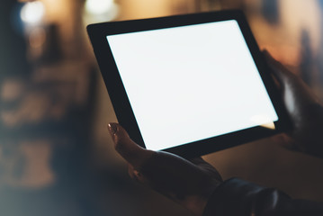 Girl holding in hands on blank screen tablet on background illumination glow bokeh light in night...