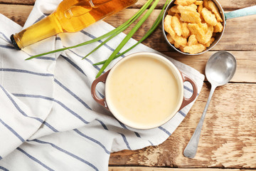 Delicious beer cheese soup with croutons on table