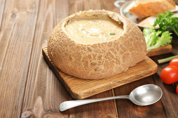 Delicious cream soup in bread on table