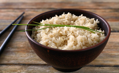 Bowl with brown rice on wooden table