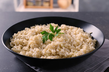 Plate with brown rice on gray table