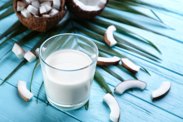 Glass of fresh coconut milk on wooden background