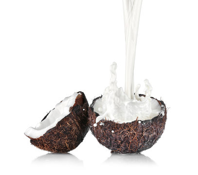 Cracked coconut with jet of milk on white background