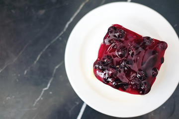 A blueberry cheese cake in white ceramic plate on marble table