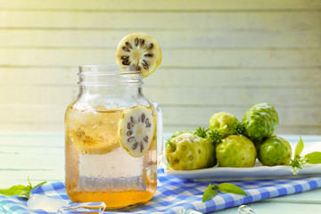 Noni herbal juice and noni fruit in the dish on wooden background.Zoom in.Menu healthy