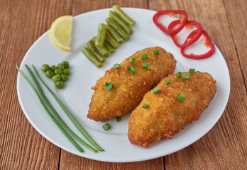 Chicken cutlets with mushrooms and vegetables on a wooden background