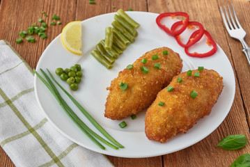 Chicken cutlets with mushrooms and vegetables on a wooden background