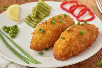 Chicken cutlets with mushrooms and vegetables on a wooden background