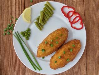 Chicken cutlets with mushrooms and vegetables on a wooden background