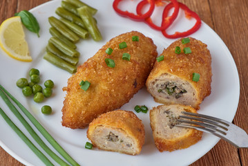 Chicken cutlets with mushrooms and vegetables on a wooden background