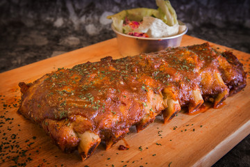 Grilled rib pork with barbecue sauce and vegetable on wooden cutting board.