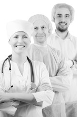 Group portrait of mixed aged medical doctors standing in hospital, looking at camera and smiling isolated on white background. Two men wearing surgeon coat and woman wearing white cap and coat.