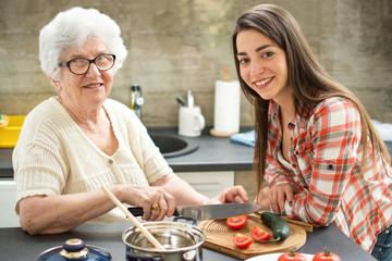 Grandmother with granddaughter cooking in the kitchen.