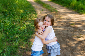 Fototapeta premium Two little girl girl friends hugging in the forest