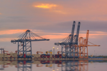 Obraz premium Logistics and transportation of Container Cargo ship and Cargo plane with working crane bridge in shipyard at Twilight sky, logistic import export background and transport industry.