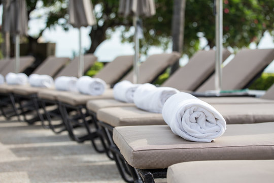 white towel roll on sunbeds at swimming pool with copy space
