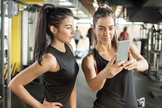Two female friends taking a selfie photo at gym.