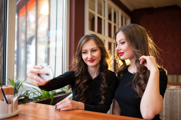 Two beautiful girls do selfi and drink coffee