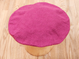 handmade felt beret is drying on wooden hat block