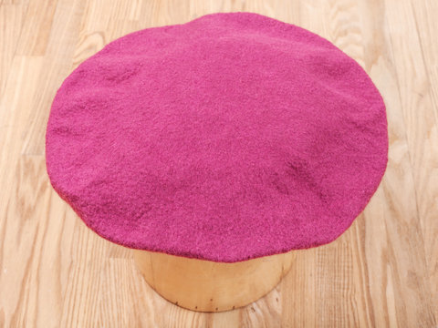 handmade felt beret is drying on wooden hat block