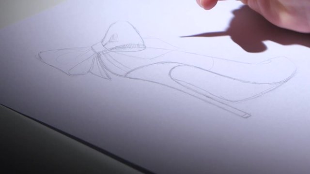 Designer smooth srih draws a sketch of beautiful female shoes. Close up