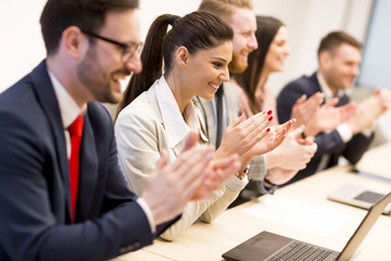 Happy smiling business team clapping hands during a meeting
