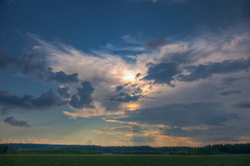 Sun shining through clouds over a wheat field