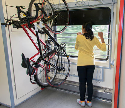 Bike hanging on the rack in the train. Transport bicycles in the wagon.Woman traveling on a train with a bicycle.