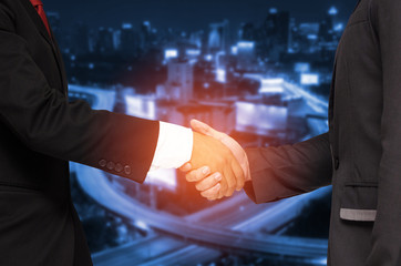Double exposure of businessman handshake, business concept, successful business meeting on blurred night city background, color tone effect.