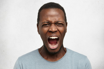 Human facial expressions, emotions and feelings. Portrait of mad angry young dark-skinned male...