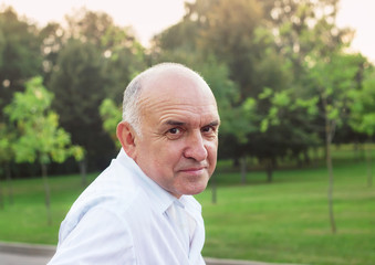 Portrait of friendly smiling senior man outdoors at sunset