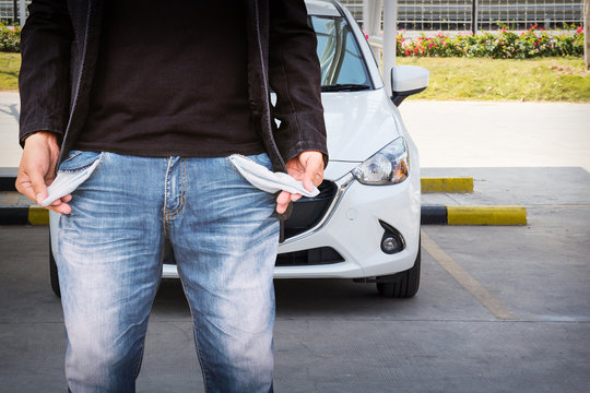 Man showing his empty pockets with white car background.