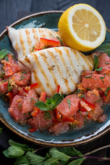 Close-up of roasted calamari served with grapefruit and mint salad on a plate, selective focus
