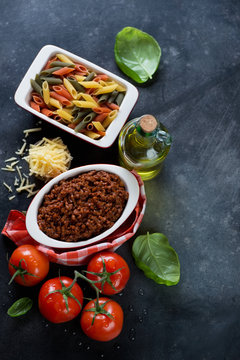 Italian bolognese sauce with raw three-colored penne pasta, high angle view with copyspace