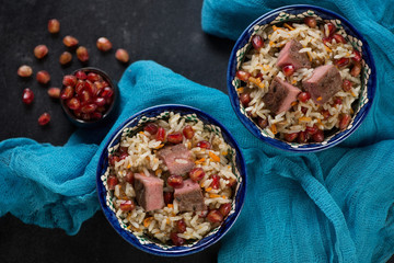 Pilaf with beef meat and pomegranate seeds served in two bowls, above view