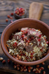 Ceramic bowl with pilaf over rustic wooden background, studio shot, close-up