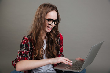 Pretty smiling young lady chatting by laptop computer