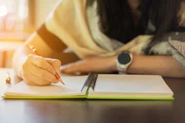 a woman working and holding red pencil and writing on notebook