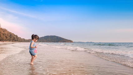 Fototapeta na wymiar little girl playing on the beach in sunset