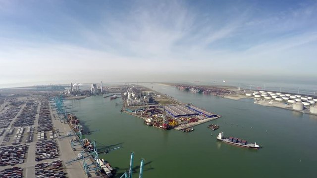 Aerial flight over harbor area industrial landscape on left side container terminal ocean containers and cranes for loading and unloading freight ships on right side oil storage containers 4k