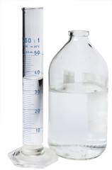 Transparent glass bottle with water and a beaker of clear liquid isolated on white background.