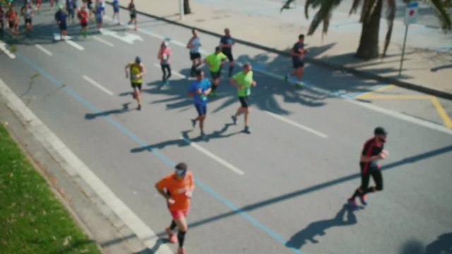 Blurred shot from the high point of the marathon runners jogging through the beach road in barcelona