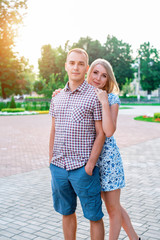 Young modern couple hugging in the park, in summer in the city, vertical, family on nature resting, concept of happy family, lifestyle.